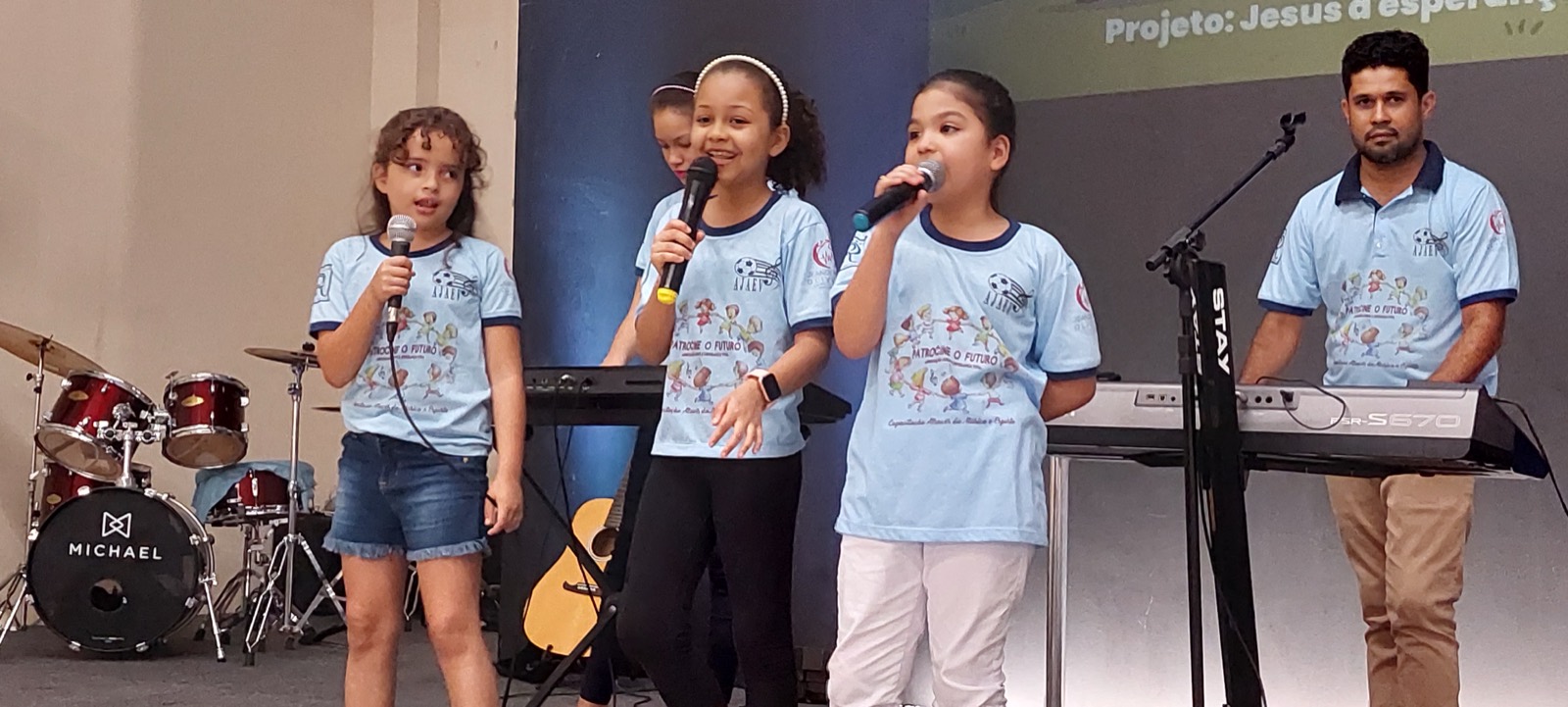 Children singing on stage in matching T-shirts