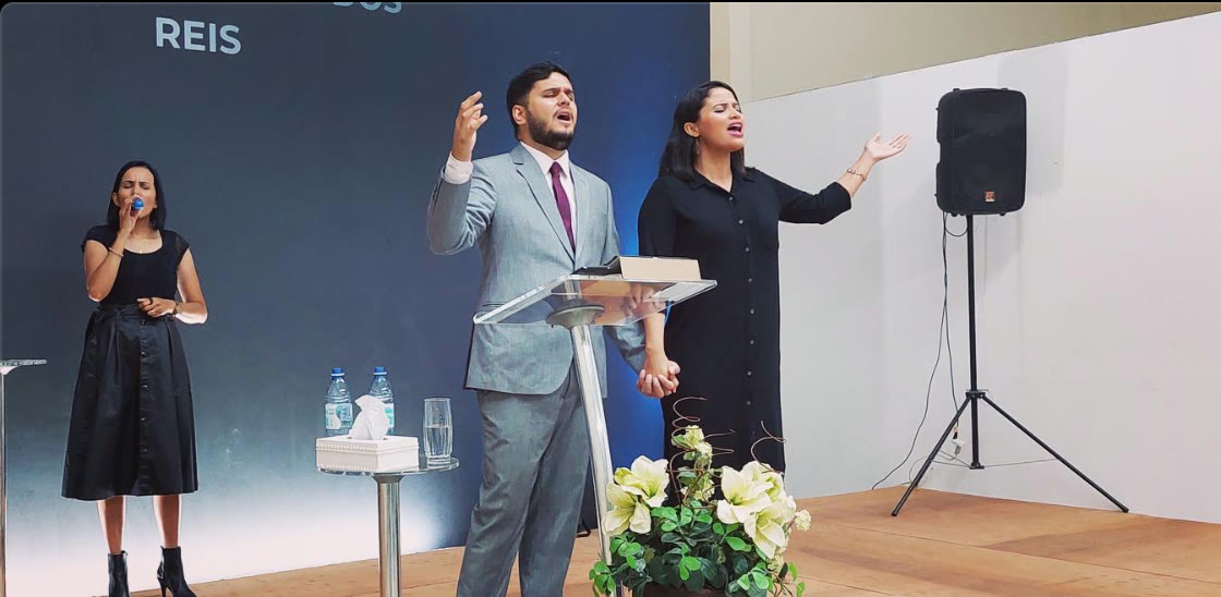 Daniel and Carla holding hands in worship at the pulpit