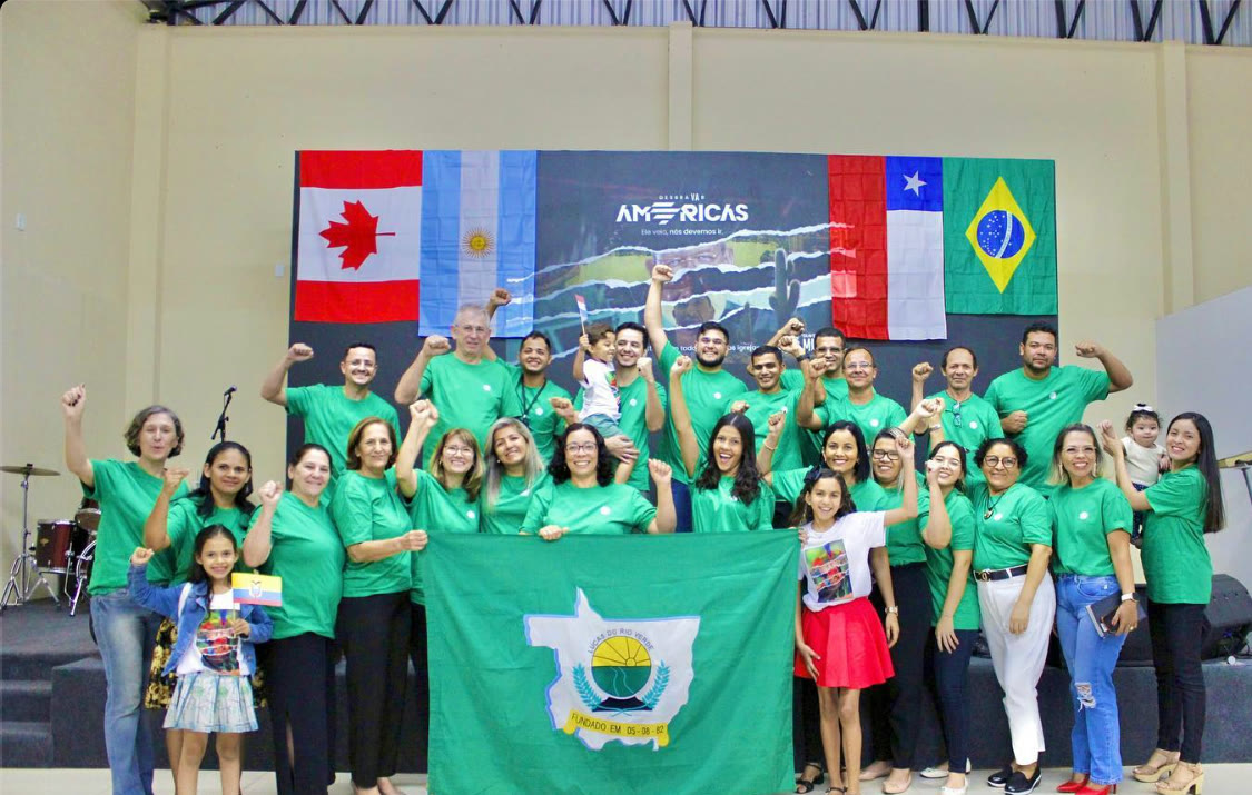 The church in green T-shirts in front of flags of the Americas, including Canada